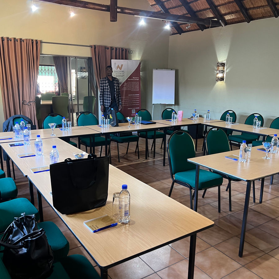A conference room arranged in a U-shaped layout with water, stationery and projection equipment.