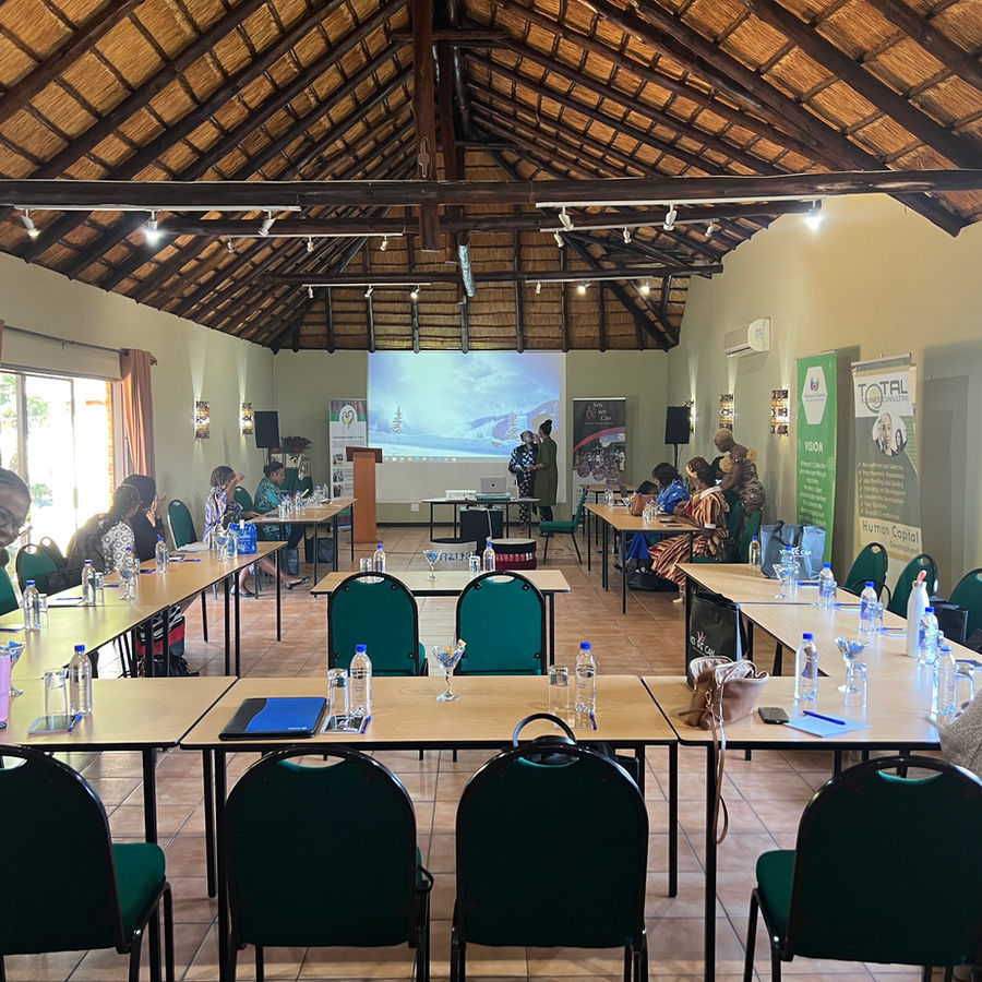 A thatched conference room arranged for a large meeting with projection and tables.