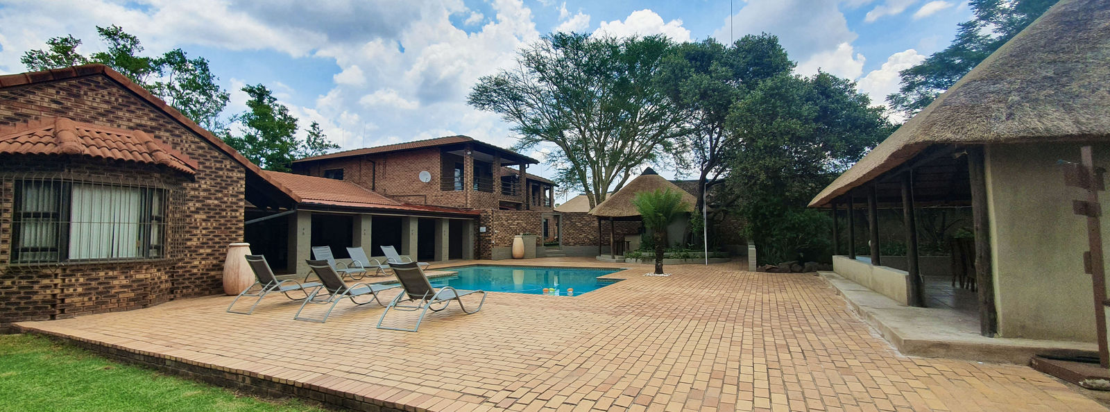 The Protea Ridge swimming pool and thatched gathering spaces surrounded by gardens.