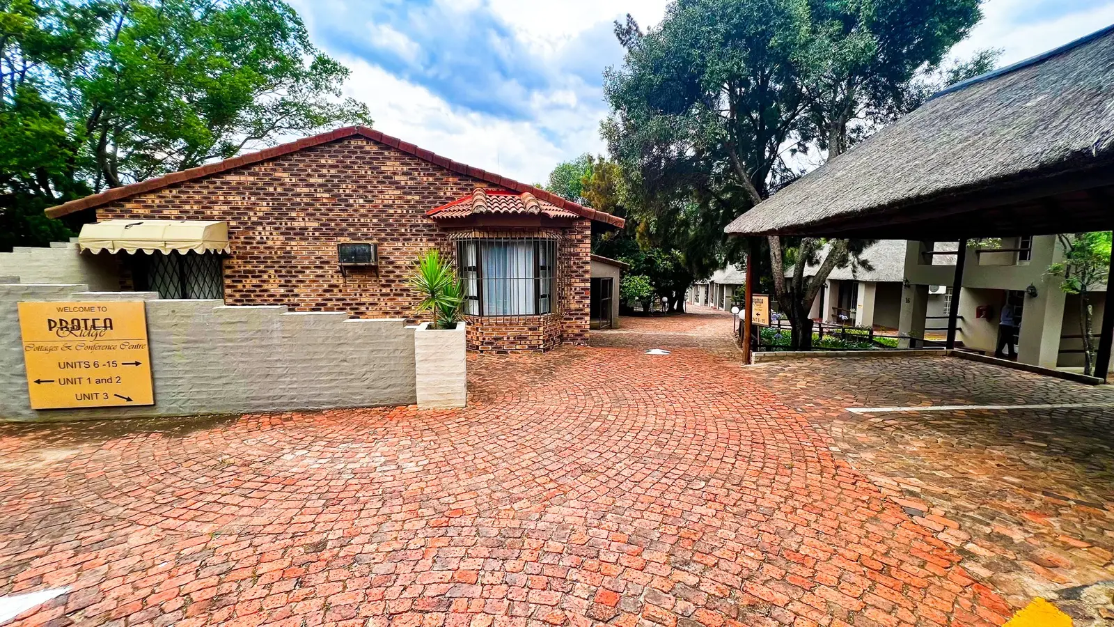 Brick and thatch accommodation around the entrance driveway at Protea Ridge.