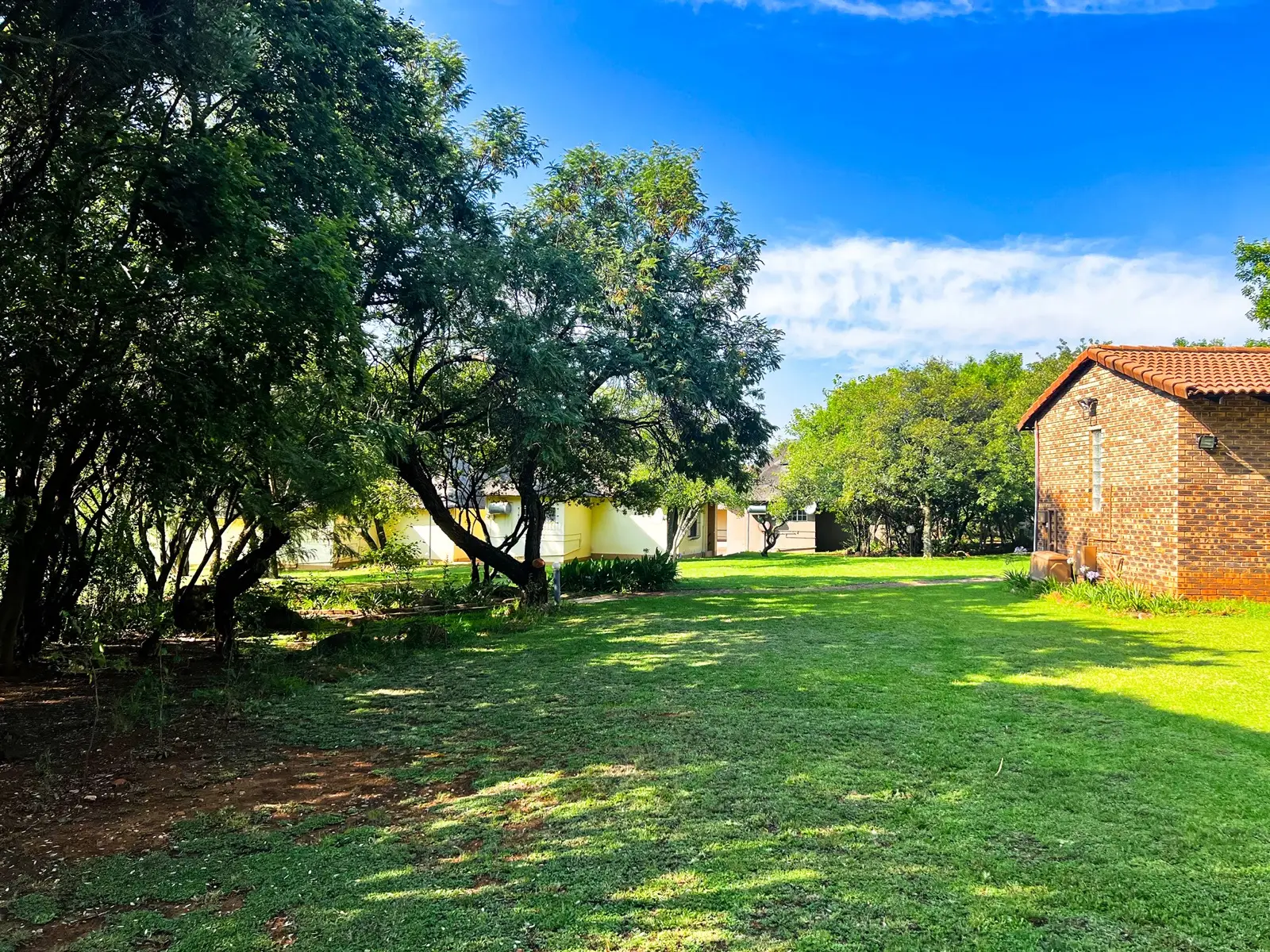 Shaded lawns and garden paths between the accommodation.