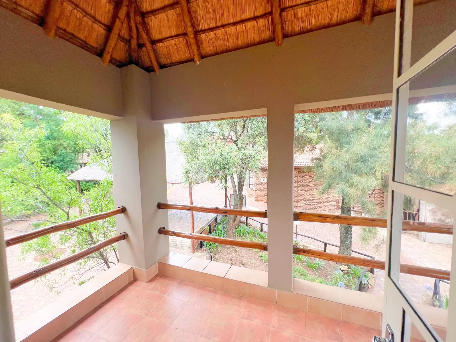 A thatched suite balcony with wooden railings overlooking the gardens.