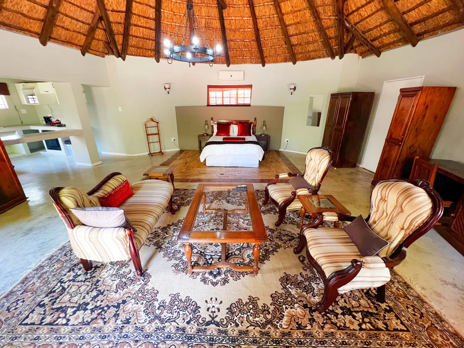 A circular thatched suite with a king bed, sitting area and exposed-beam ceiling.