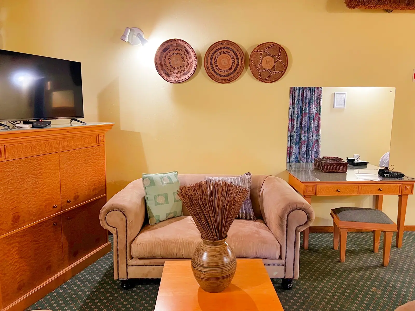 A suite lounge with a leather sofa, television and work desk.