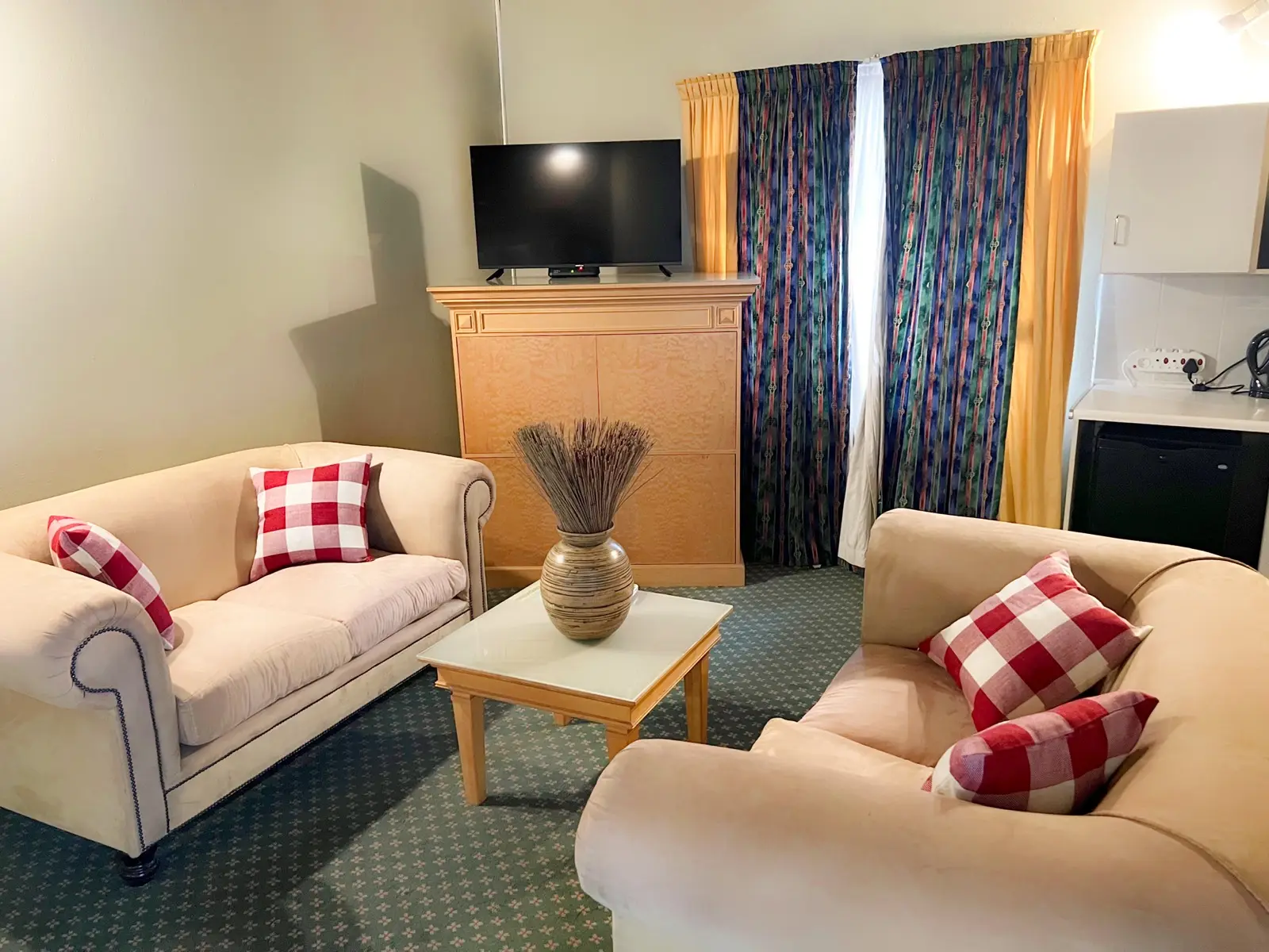 A sitting area with cream sofas and red scatter cushions.
