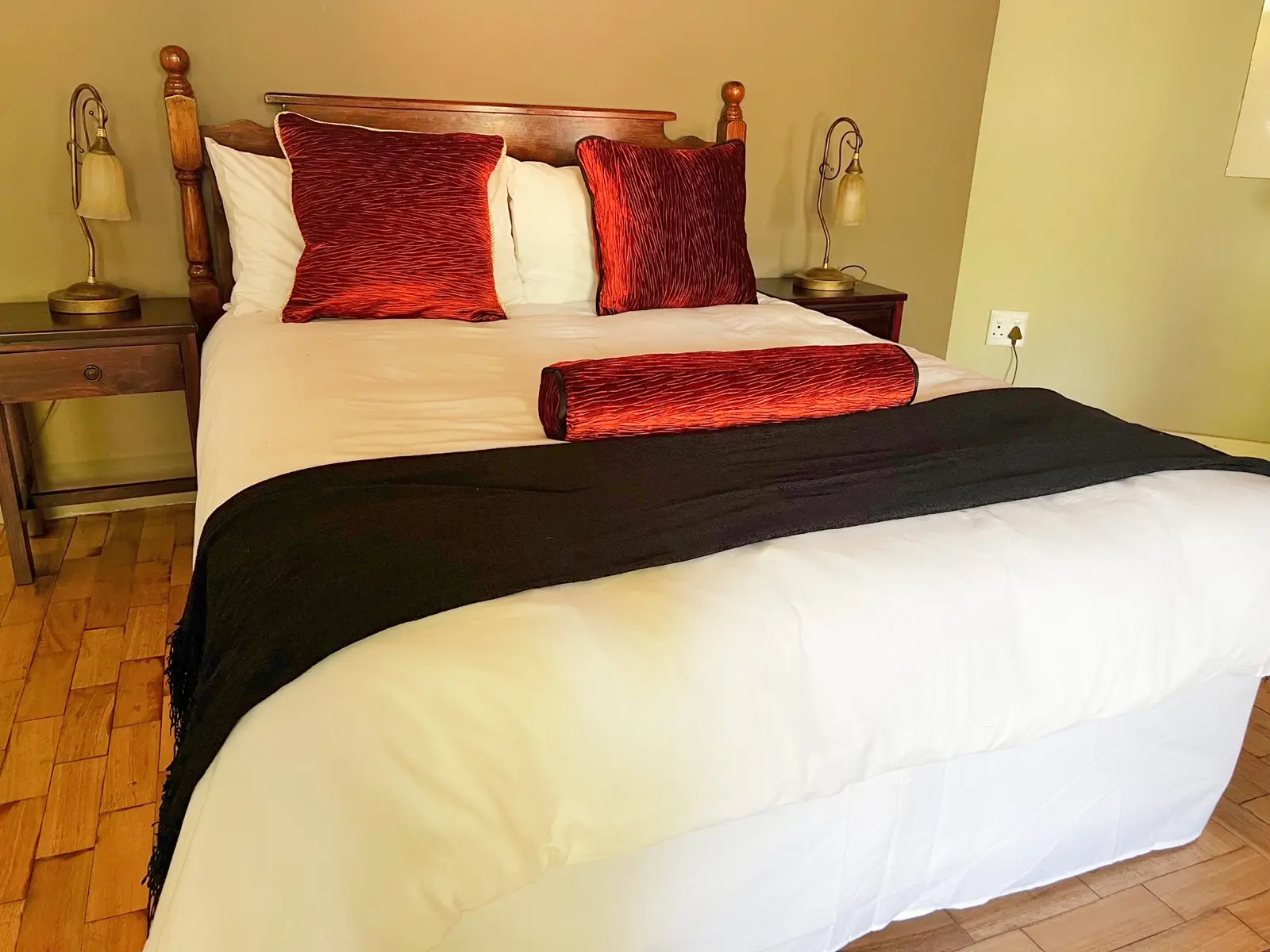 A bedroom with a dark bed runner and warm bedside lighting.
