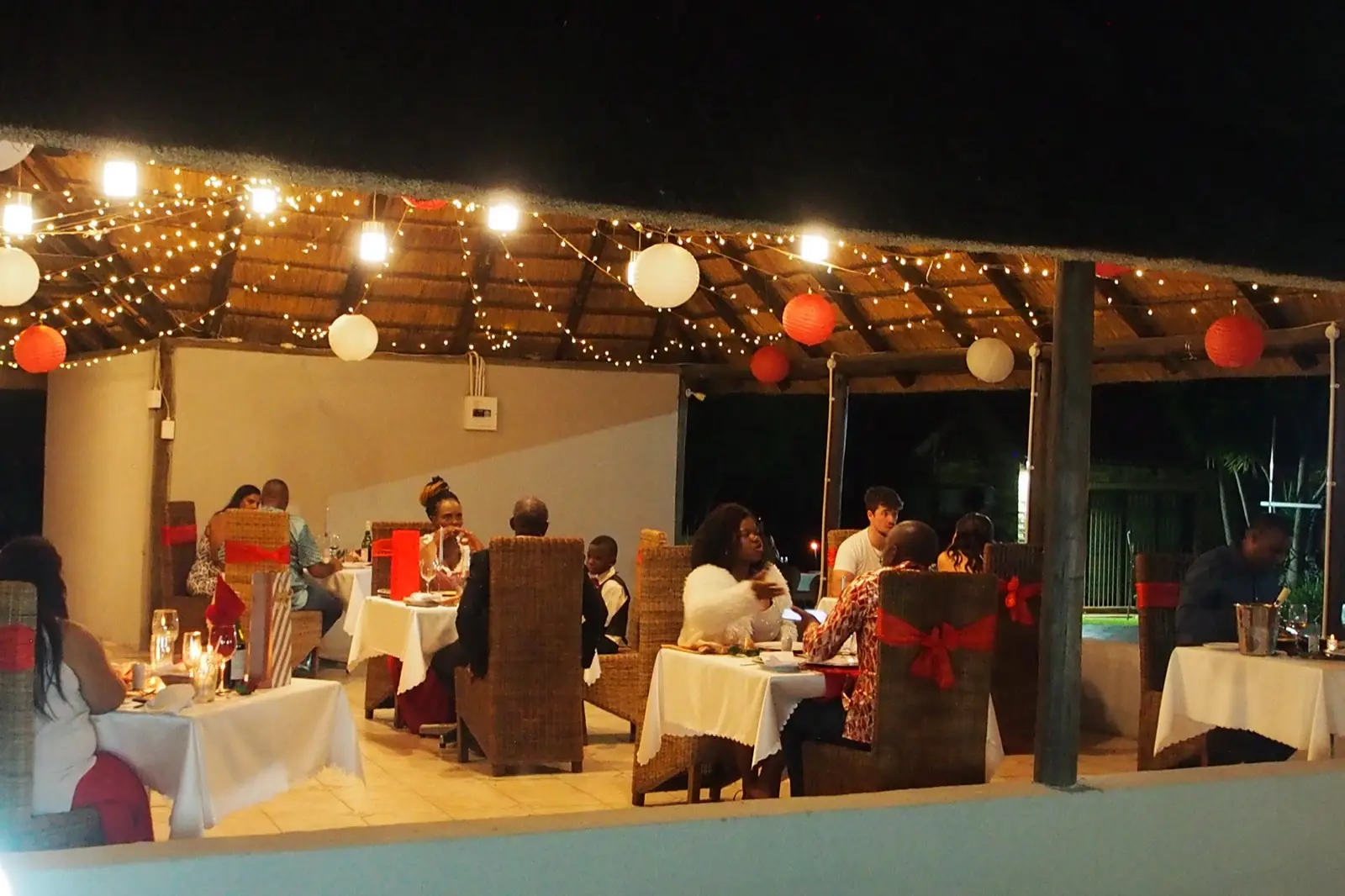 An evening reception beneath string lights and paper lanterns.