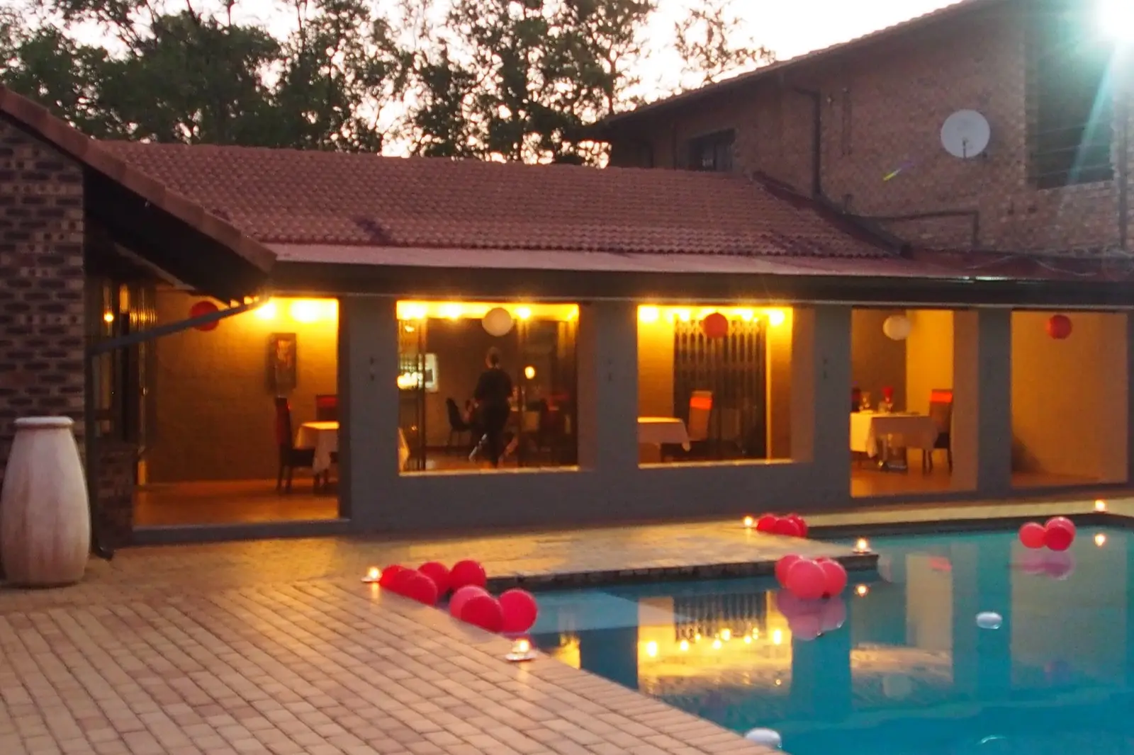 A thatched suite and pool lit for an evening celebration.