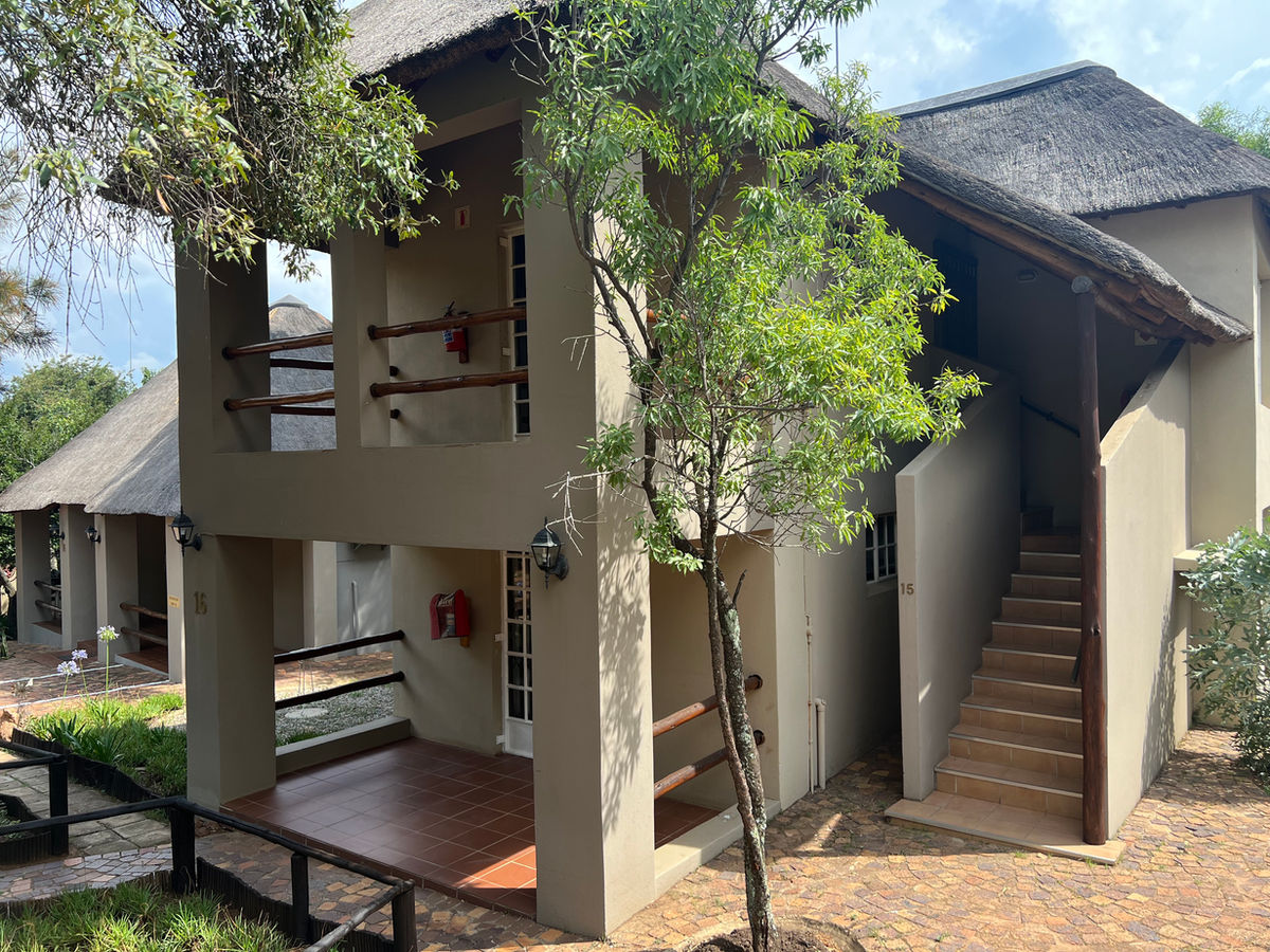 Thatched accommodation buildings connected by a garden walkway at Protea Ridge Lodge.