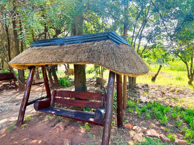 A wooden garden swing beneath the trees at Protea Ridge Lodge.