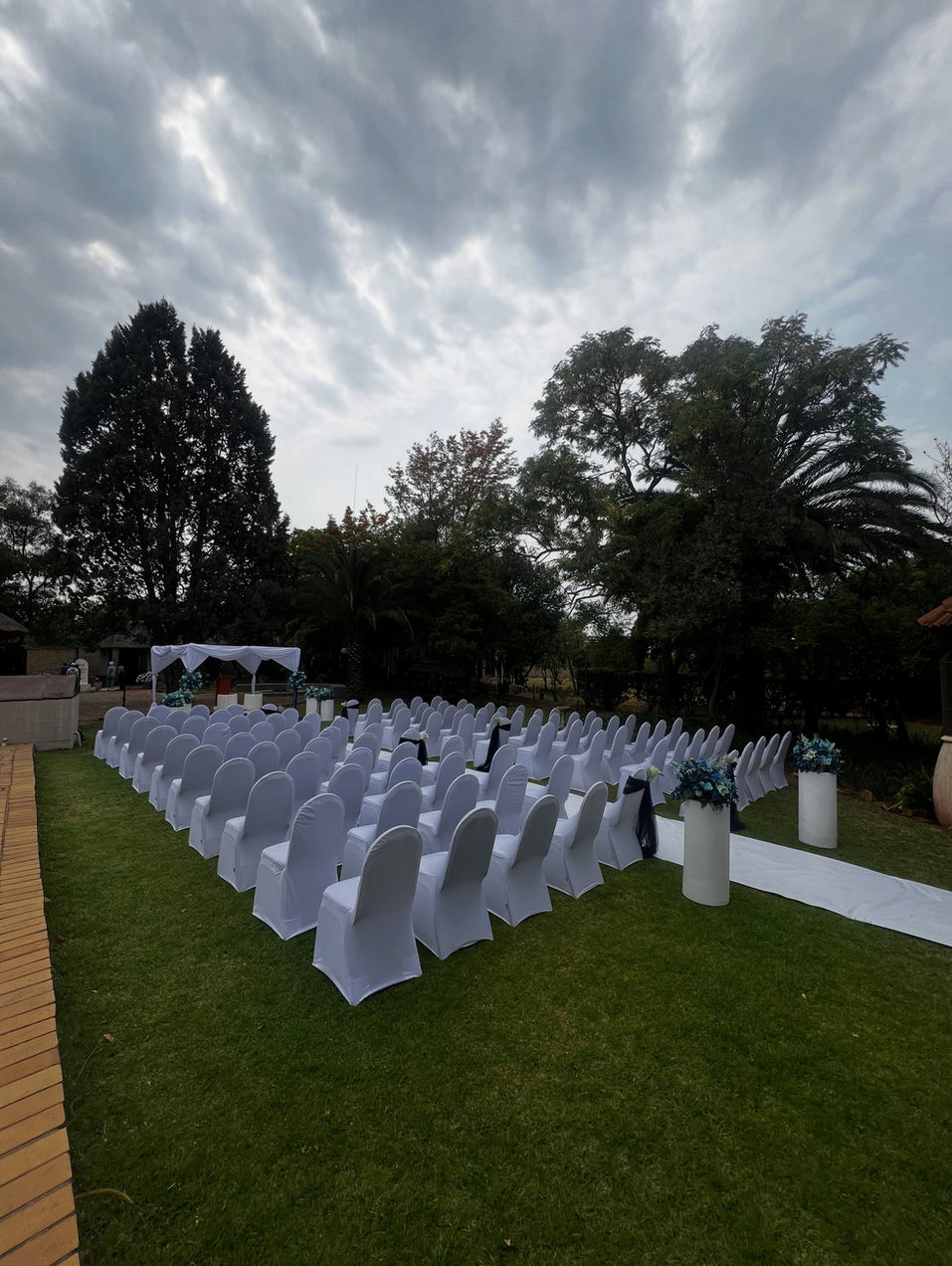 An outdoor wedding ceremony arranged on the lodge lawn beneath mature trees.