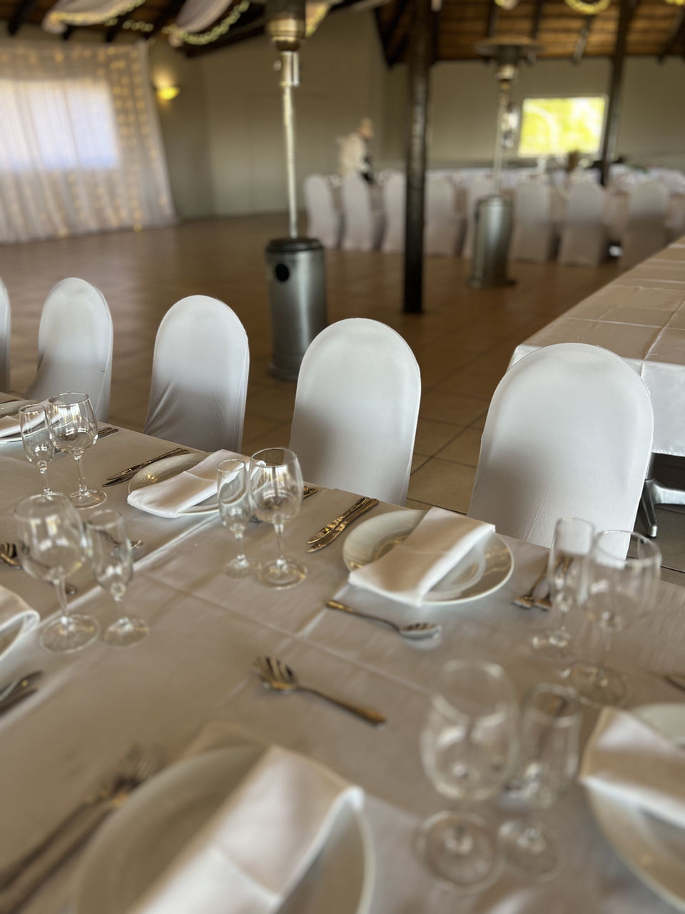 A wedding table set with white linen, glassware and place settings.