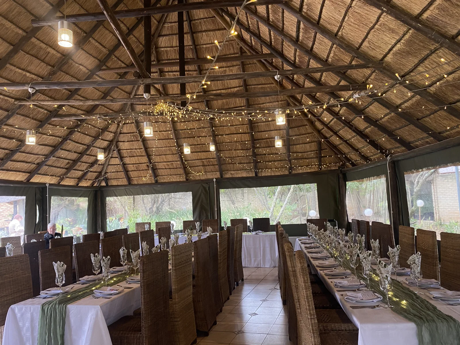 Long banquet tables arranged beneath the thatched venue roof.