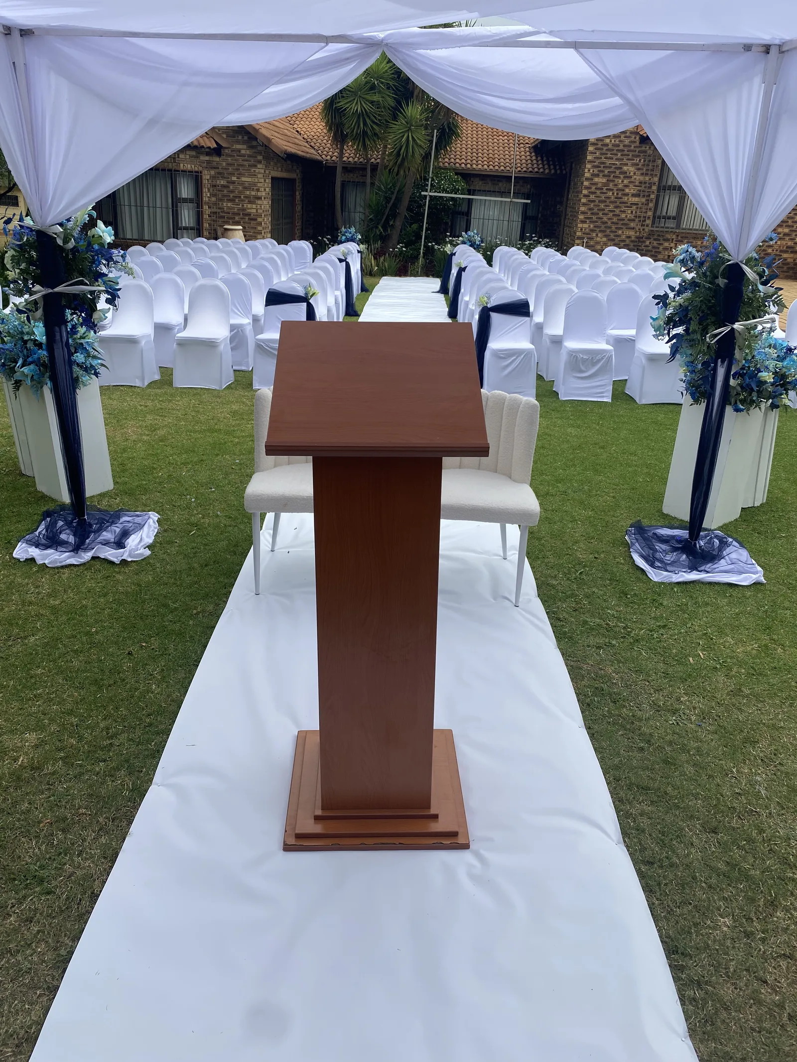 A garden wedding ceremony setup with a lectern and white draping.