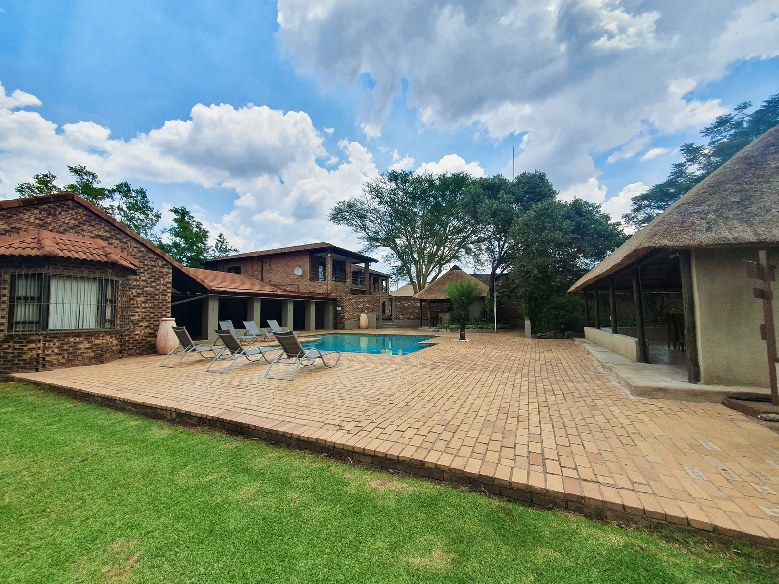 The swimming pool, sun loungers, cottages and thatched lapa at Protea Ridge.