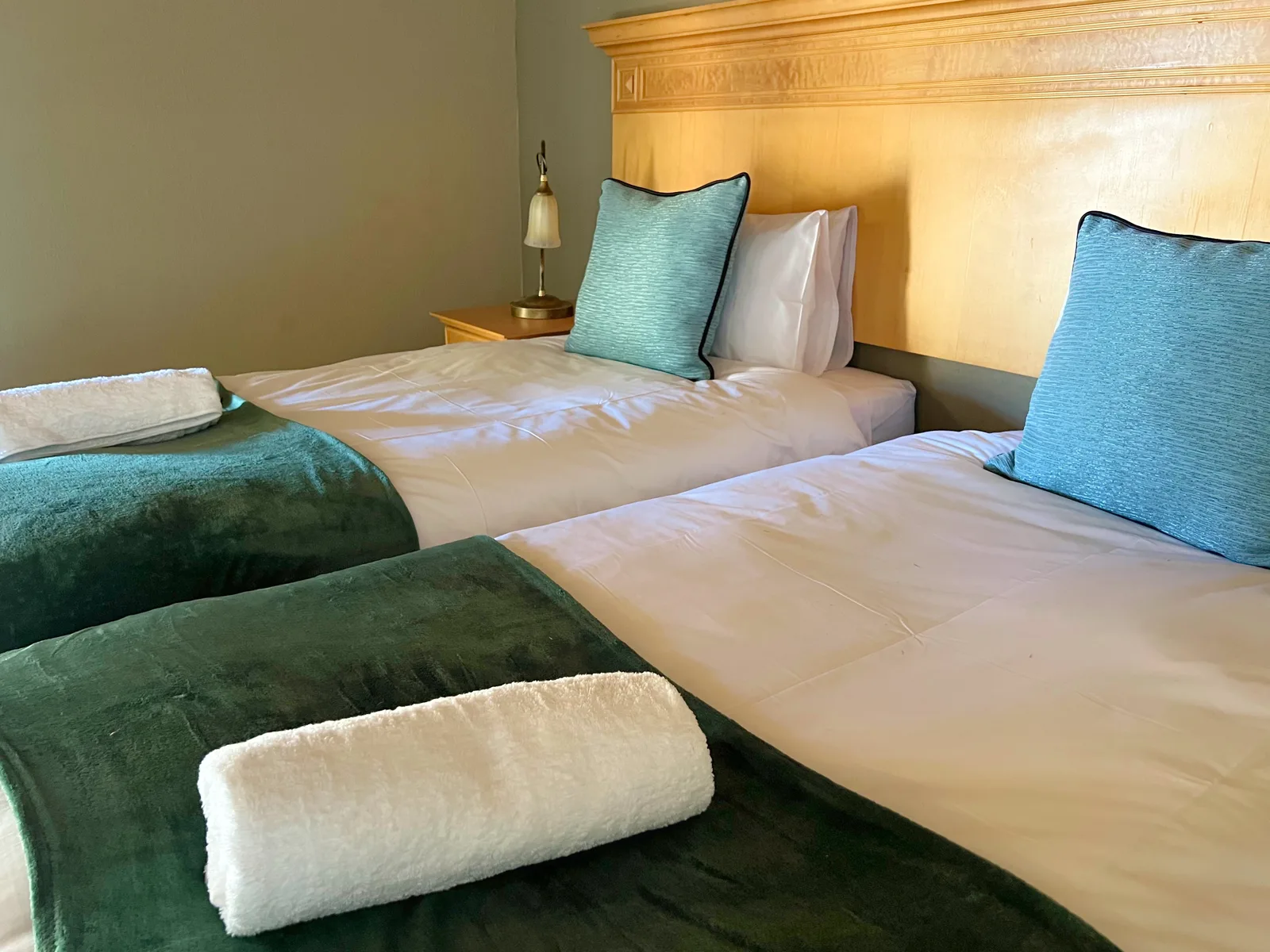Twin beds with blue cushions and folded towels in a guest cottage.